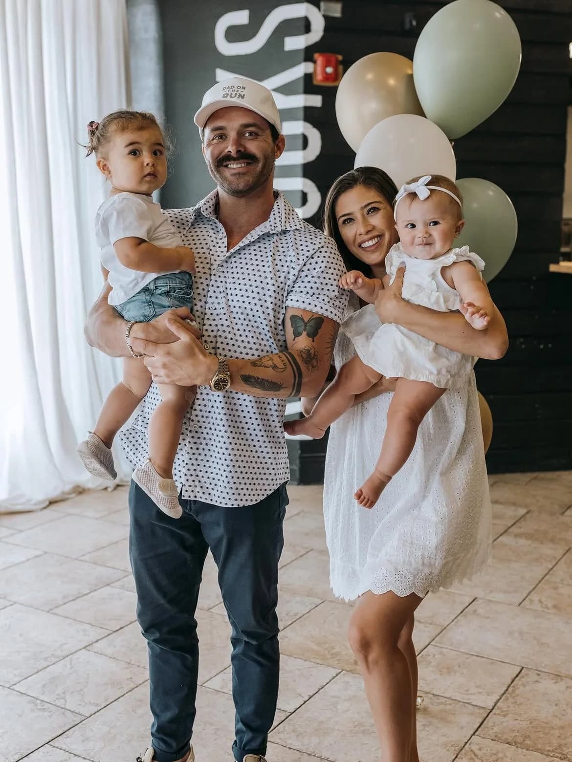 April and Cody holding their two little girls in front of balloons